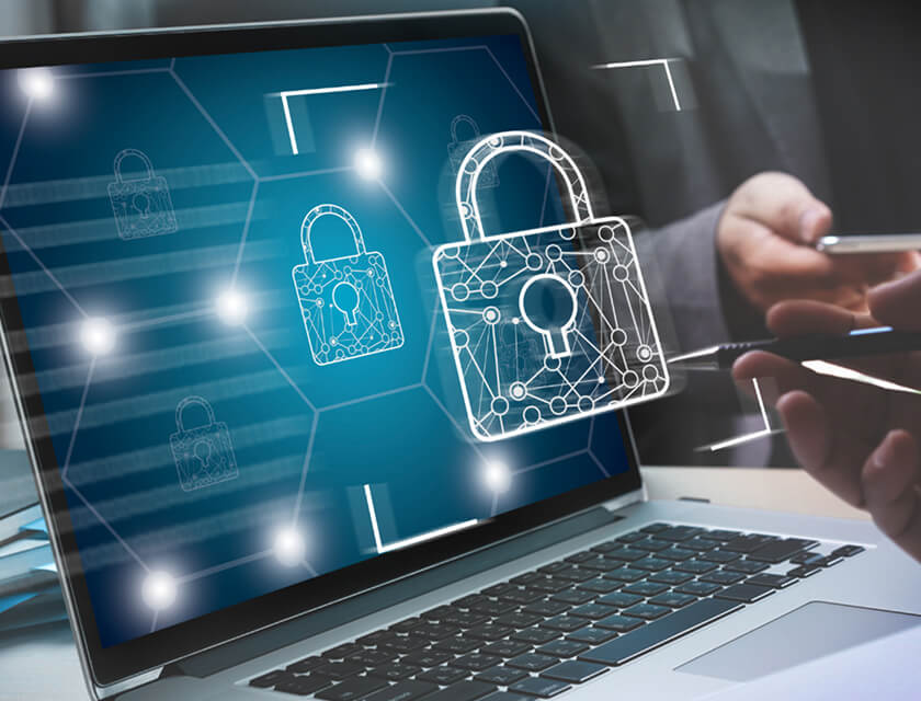 A laptop screen displays digital padlocks symbolizing cybersecurity. A hand gestures in the background, suggesting interaction or communication. The foreground includes a glowing lock with circuit-like patterns, highlighting how commercial insurance plays a vital role in data protection.